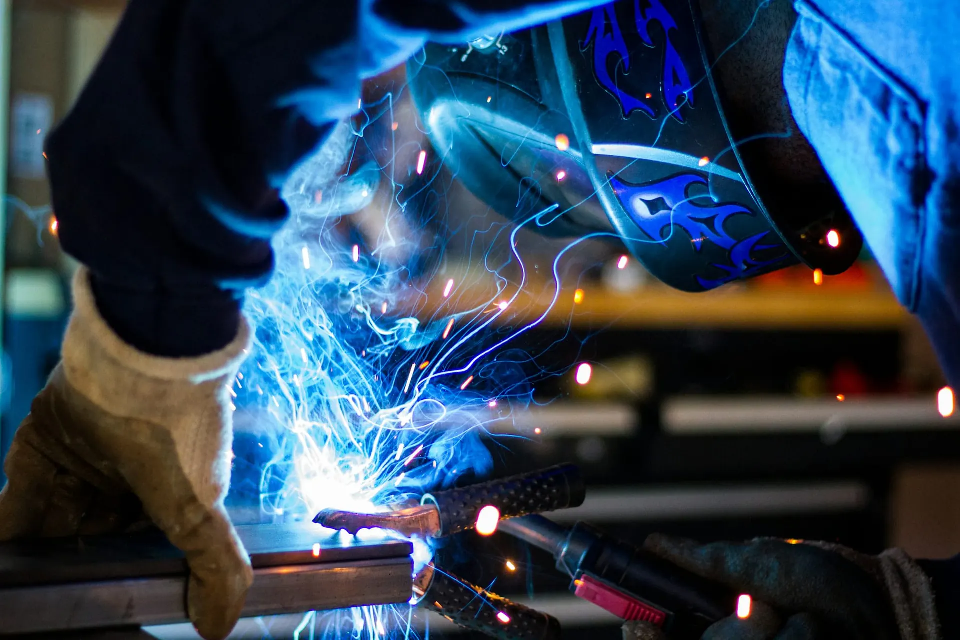 Welder fabricating steel under blue arc light