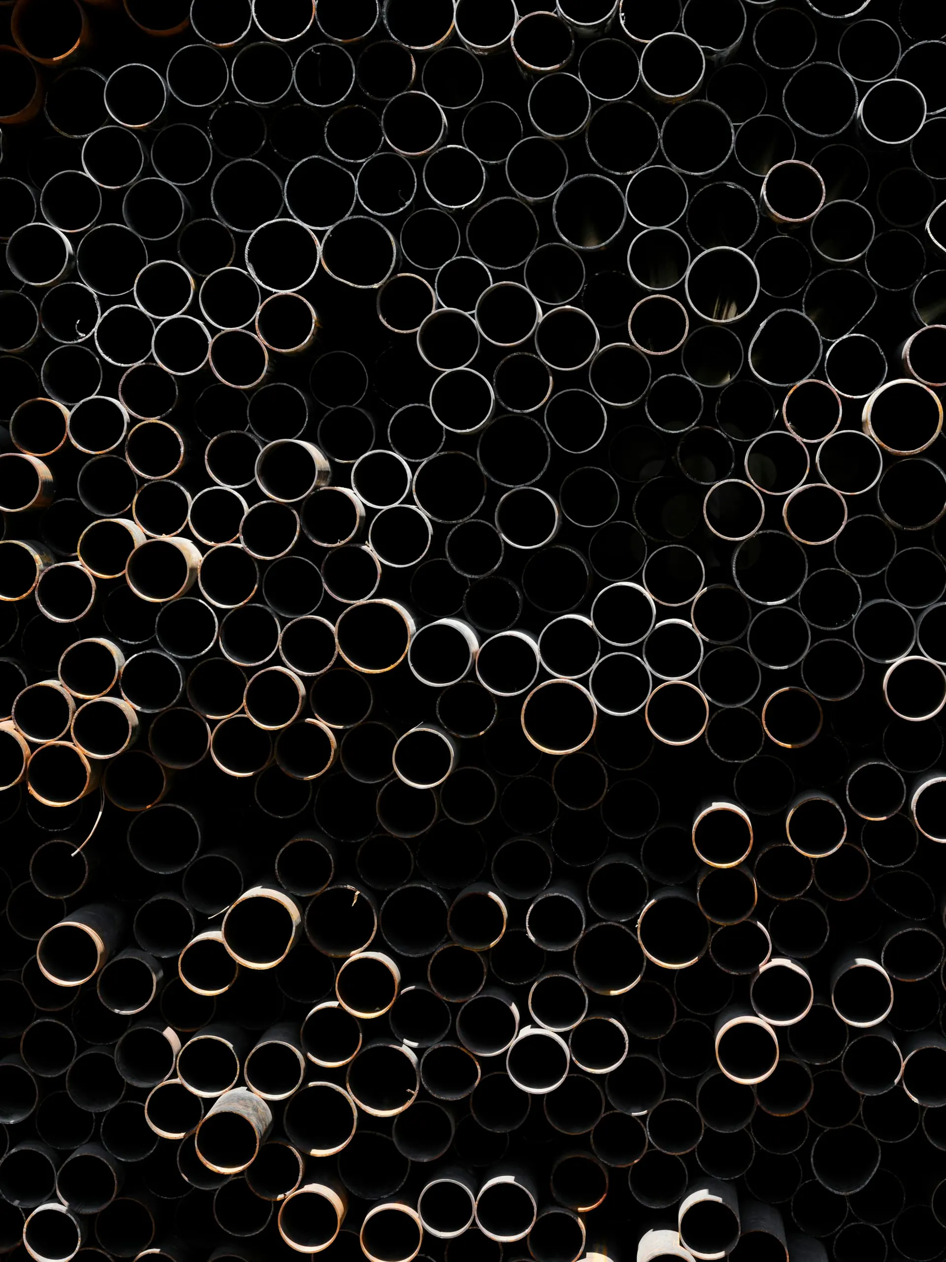 Close-up of black steel pipe ends in a stack